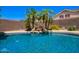 Backyard pool with waterfall feature and lush landscaping, set against a blue sky at 25633 N 71St Dr, Peoria, AZ 85383