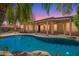 Backyard pool view with lush landscaping, covered patio and dusk sky in the background at 25633 N 71St Dr, Peoria, AZ 85383