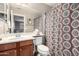 Well-lit bathroom featuring wood cabinets, a sink, a toilet, and a patterned shower curtain at 4043 E Carla Vista Dr, Gilbert, AZ 85295