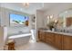 Luxurious bathroom featuring a soaking tub, modern fixtures, a double vanity, and sunlit windows at 7328 E Laredo Ln, Scottsdale, AZ 85250