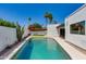 Backyard swimming pool surrounded by lush desert landscaping, bright blue sky, and a white privacy wall at 7328 E Laredo Ln, Scottsdale, AZ 85250