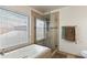 This is a bathroom with a glass shower, soaking tub, and large window at 7649 W Dahlia Dr, Peoria, AZ 85381