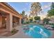 This serene backyard features a pool, a covered patio, lush landscaping, and mature trees at 8036 E Mercer Ln, Scottsdale, AZ 85260