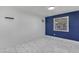 Bedroom showcases a navy accent wall, air conditioning unit, bright window and stylish tile flooring at 8132 W Pierson St, Phoenix, AZ 85033