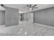Spacious living room with gray walls, white trim, tiled floors, and a modern ceiling fan at 8132 W Pierson St, Phoenix, AZ 85033