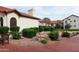 View of a residential building exterior featuring red tile roof, manicured bushes and shrubbery, and brick paved walkways at 11011 N 92Nd St # 1005, Scottsdale, AZ 85260