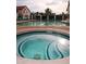 Community pool and separate jacuzzi tub featuring teal tiles, lounge chairs, mature trees, and shade umbrellas at 11011 N 92Nd St # 1005, Scottsdale, AZ 85260