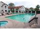 Community pool with lounge chairs, umbrellas, mature trees, greenery, and a building with a red tile roof at 11011 N 92Nd St # 1005, Scottsdale, AZ 85260