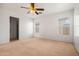 Spacious bedroom features neutral carpeting, ceiling fan, and bright, natural light from two windows at 11710 W Paradise Dr, El Mirage, AZ 85335