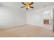 Carpeted bedroom with neutral walls and ceiling fan, leading to tiled hallway and stairs at 11710 W Paradise Dr, El Mirage, AZ 85335