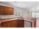 Well-lit kitchen features light countertops, wooden cabinetry, a double sink, and backyard views at 11710 W Paradise Dr, El Mirage, AZ 85335