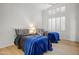 Cozy bedroom showcasing two twin beds with blue blankets, light wood floors, and white walls with window shutters at 11993 E Mission Ln, Scottsdale, AZ 85259