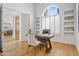 Inviting home office featuring custom built-ins, wood floors, arched window, and ample natural light for productivity at 11993 E Mission Ln, Scottsdale, AZ 85259