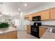 Open kitchen view with tile floors, wood cabinets, and black appliances at 12355 W Hadley St, Avondale, AZ 85323