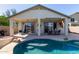 Backyard features a covered patio, swimming pool, landscaped terrace, and exterior with light colored stucco at 14895 W Jenan Dr, Surprise, AZ 85379