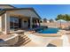 Backyard features a covered patio, swimming pool, landscaped terrace, and exterior with light colored stucco at 14895 W Jenan Dr, Surprise, AZ 85379