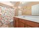 Bathroom with a wooden vanity, patterned shower curtain, and beige walls and flooring at 14895 W Jenan Dr, Surprise, AZ 85379