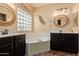 Elegant bathroom featuring dual sinks, a soaking tub, and decorative mirrors at 14895 W Jenan Dr, Surprise, AZ 85379
