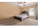 Carpeted bedroom with ceiling fan and a window with curtains allowing natural light to brighten the space at 14895 W Jenan Dr, Surprise, AZ 85379