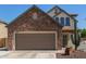 Home exterior featuring a two-car garage and stone facade with desert landscaping at 14895 W Jenan Dr, Surprise, AZ 85379