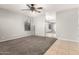 Spacious living room with neutral paint, plush carpeting, and modern ceiling fan with tile entryway at 14919 W Hearn Cir, Surprise, AZ 85379