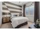 Warm-toned bedroom with decorative accent wall, and window with neutral curtains at 16373 W Beautiful Ln, Goodyear, AZ 85338