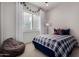 Cozy bedroom with a blue plaid bedspread, window with white blinds, and a plush beanbag chair at 16373 W Beautiful Ln, Goodyear, AZ 85338
