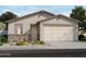 Charming single-story home featuring a two-car garage and stone accents, surrounded by lush landscaping at 17303 W Eva St, Waddell, AZ 85355