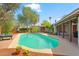An inground pool surrounded by well-manicured landscaping and brickwork with a covered porch at 1749 W Monterosa St, Phoenix, AZ 85015