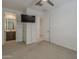 Carpeted bedroom featuring a mounted TV, access to a full bath, and a ceiling fan at 17704 W Fetlock Trl, Surprise, AZ 85387