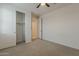 This cozy bedroom features neutral carpeting, a ceiling fan, and a spacious closet at 17704 W Fetlock Trl, Surprise, AZ 85387