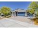 Single-story home with blue garage doors, desert landscaping, and paved driveway at 17704 W Fetlock Trl, Surprise, AZ 85387