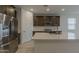 Open kitchen has stainless steel appliances, gray cabinets, and a kitchen island with quartz countertops at 17704 W Fetlock Trl, Surprise, AZ 85387