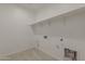 Well-lit laundry room with ample wall shelving, utility connections, and LVP flooring at 17704 W Fetlock Trl, Surprise, AZ 85387