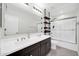 Bathroom featuring dual sinks, large mirror, and tub with sliding glass door at 19026 W Becker Ln, Surprise, AZ 85388