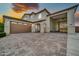 Home exterior featuring a paver driveway and garages with neutral paint and brick accents at 19026 W Becker Ln, Surprise, AZ 85388
