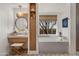 Luxurious bathroom with a vanity, built-in storage, a soaking tub, and a makeup vanity next to a window at 19296 N 98Th Pl, Scottsdale, AZ 85255