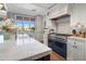 Bright kitchen featuring farmhouse sink, white cabinetry, marble countertops, and stainless steel appliances at 19296 N 98Th Pl, Scottsdale, AZ 85255