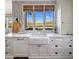 Bright kitchen featuring farmhouse sink, white cabinetry, marble countertops, and stainless steel appliances at 19296 N 98Th Pl, Scottsdale, AZ 85255