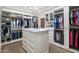 Spacious walk-in closet with custom shelves, an island with drawers, and a chandelier for lighting at 19296 N 98Th Pl, Scottsdale, AZ 85255
