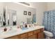 Well-lit bathroom with a double sink vanity, large mirror, and patterned shower curtain at 1955 E Grand Canyon Dr, Chandler, AZ 85249
