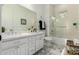 Bright bathroom with a double sink vanity, a decorative mirror, fresh black and white accent towels, and shower with glass door at 2879 E Austin Dr, Gilbert, AZ 85296