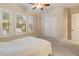 Bright bedroom featuring a ceiling fan, shuttered windows, and a cozy quilt-covered bed at 31207 N 124Th Dr, Peoria, AZ 85383