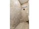 An elegant shower space with light stone-patterned tile and a dark, modern shower head at 31207 N 124Th Dr, Peoria, AZ 85383