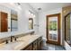 Well-lit bathroom featuring double sinks, granite countertops, and a door to the outdoors at 3160 E Fox St, Mesa, AZ 85213