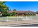 Well-maintained home exterior with lush green lawn, mature trees, and charming white picket fence at 3160 E Fox St, Mesa, AZ 85213
