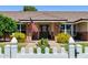 Charming home entrance with brick accents, American flag, mature landscaping, and white picket fence at 3160 E Fox St, Mesa, AZ 85213
