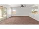 Bright living room with sliding glass door and neutral carpeting, illuminated by a modern ceiling fan at 3221 W Alta Vista Rd, Phoenix, AZ 85041