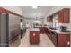 Well-lit kitchen features stainless steel appliances, wooden cabinetry, tile flooring, and center island at 3424 E Harmony Ave, Mesa, AZ 85204