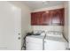 Functional laundry room with overhead cabinets and essential appliances offers convenience at 3424 E Harmony Ave, Mesa, AZ 85204